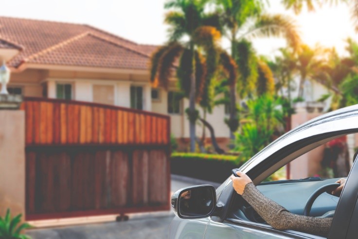 Woman in a car opening a sliding gate using a remote control