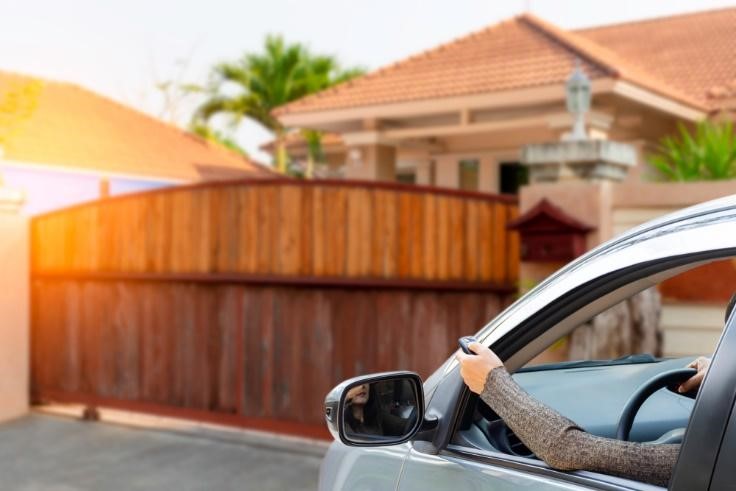 Woman in car opening sliding gate using a remote control