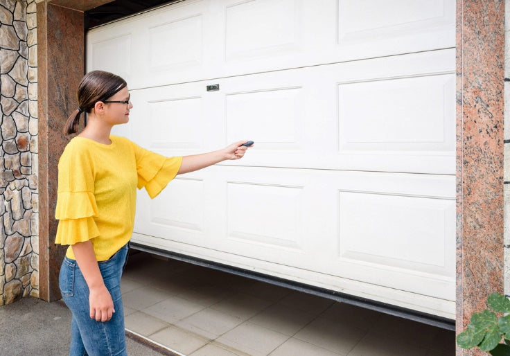Woman pressing remote control to open garage door