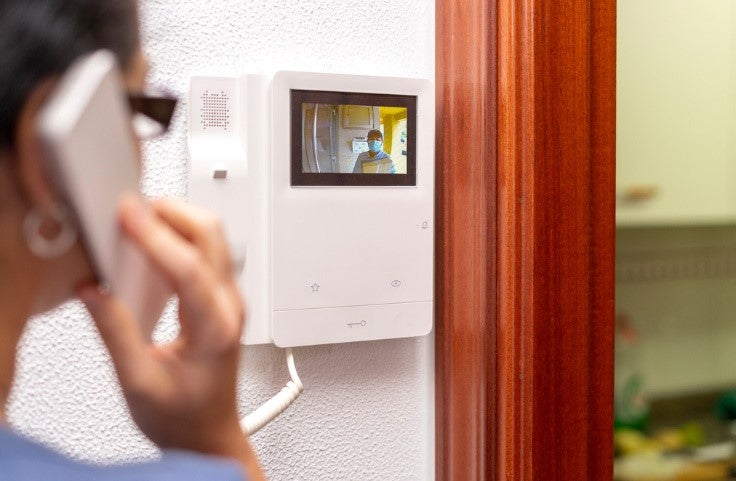 Woman talking to delivery guy through intercom phone