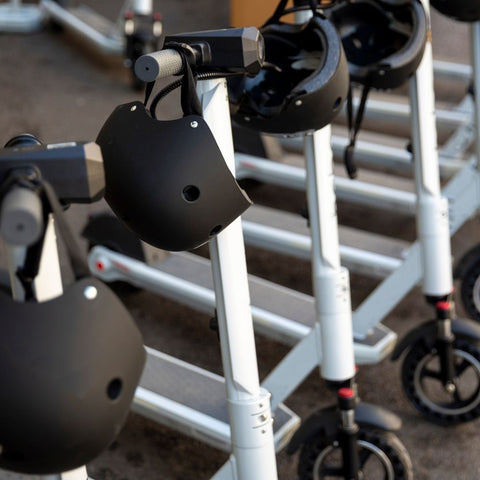 electric scooters lined up in a row with helmet on the steering handles