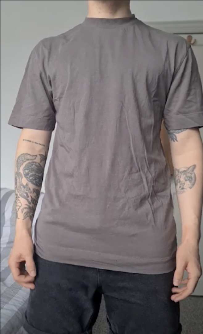 Transmasc person wearing cis-fit shirt that is too long for their body