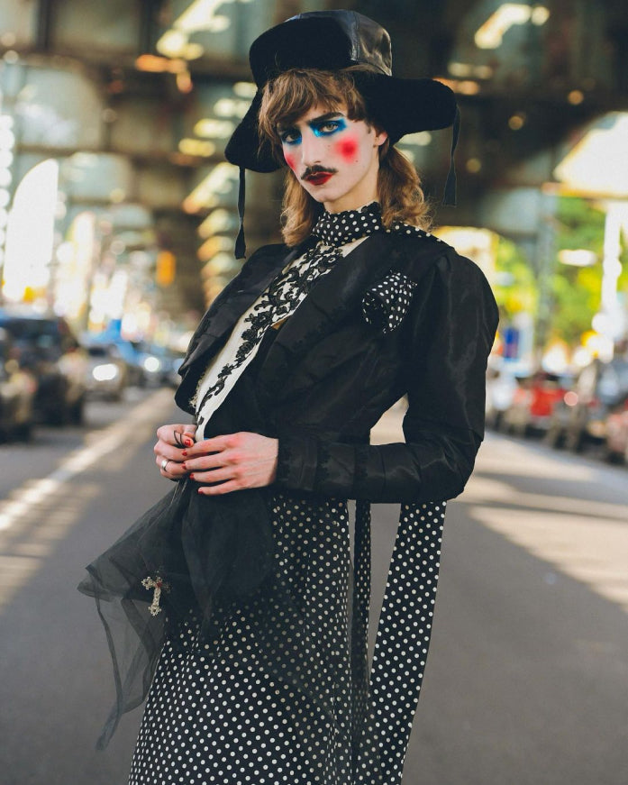 Niko Haagenson in a gender-nonconforming outfit, featuring black polka dot dress and makeup