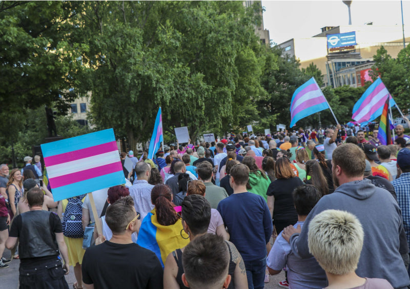 Transgender pride march held by GLAAD with protesters walking together holding up transgender pride flags