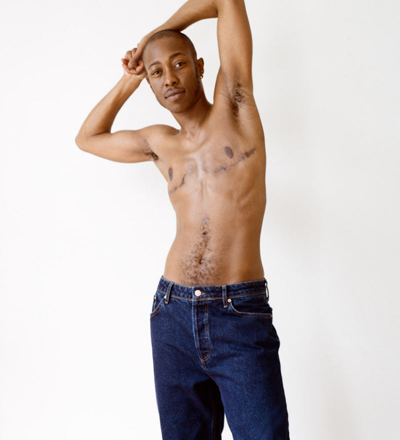Transmasc model shirtless with top surgery scars, wearing Both& Jo denim jeans