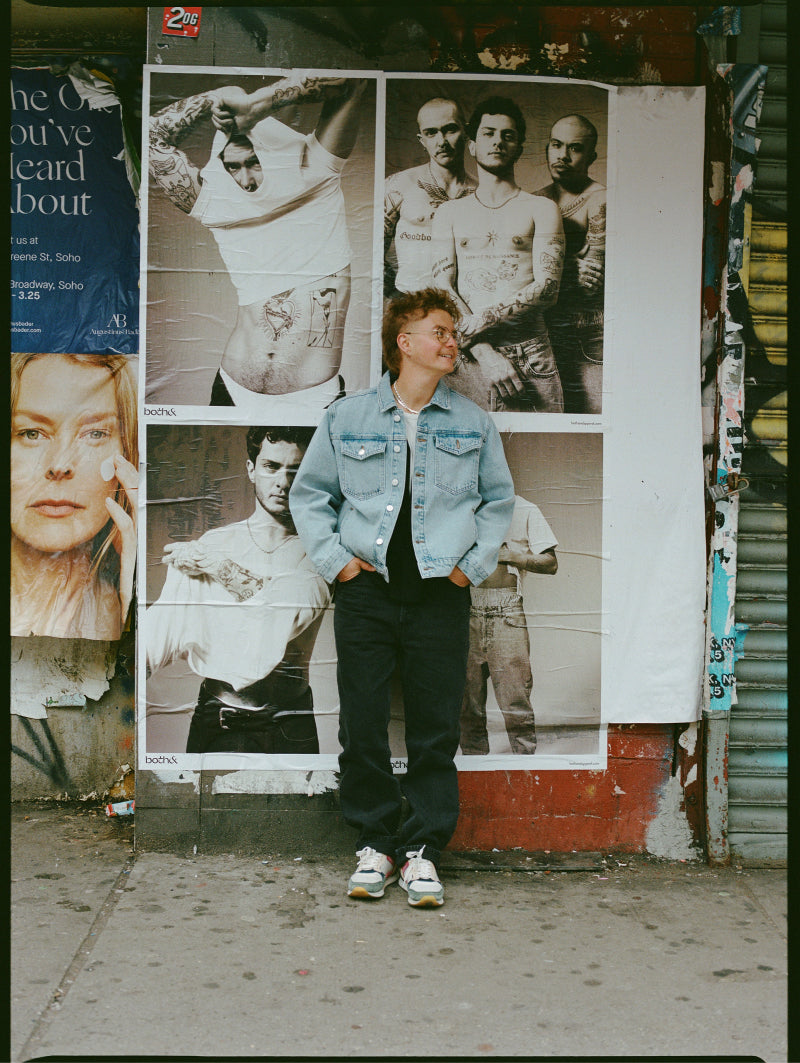 Finn smiling and standing in front of Boys Boys Boys campaign wild postings