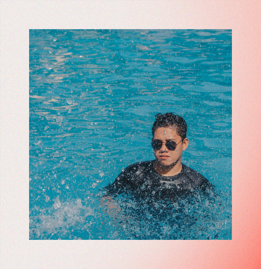 Nonbinary person wearing sunglasses and shirt in pool