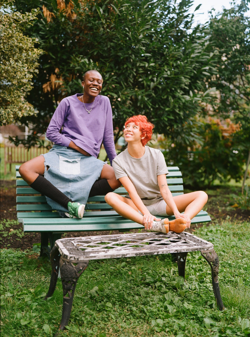 Two queer friends hanging out at a park bench