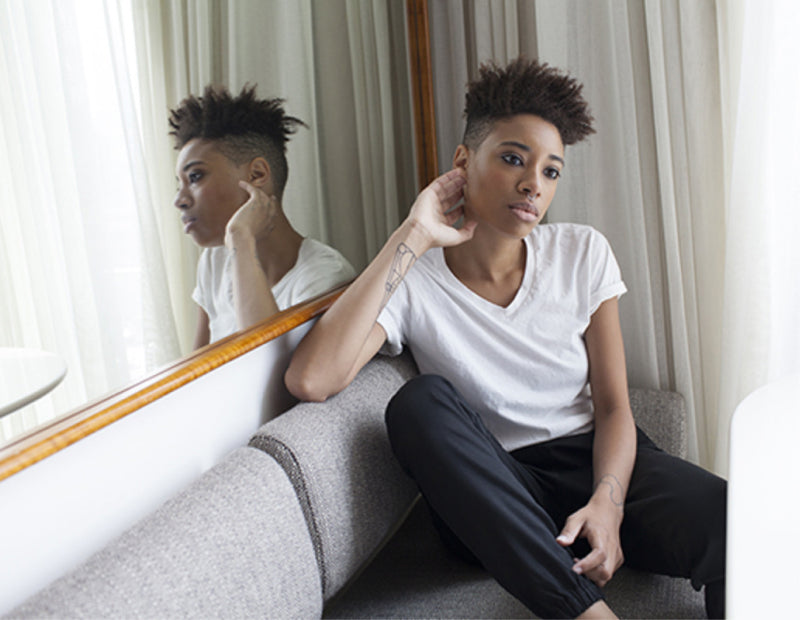 Black woman wearing white v-neck shirt and dark trackpants