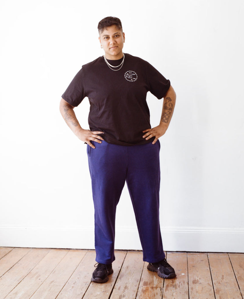 Nonbinary model wearing black tee and royal blue Jeremiah sweatpants