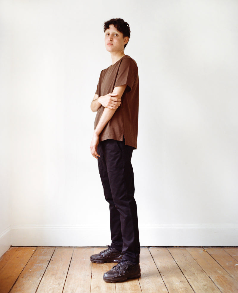 Trans model in brown tee and black Marlo pants