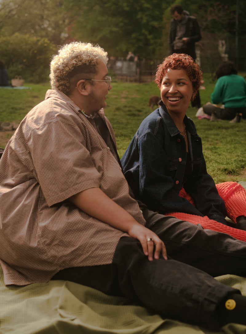 Trans Couple enjoys a picnic outside at a park and smile at each other