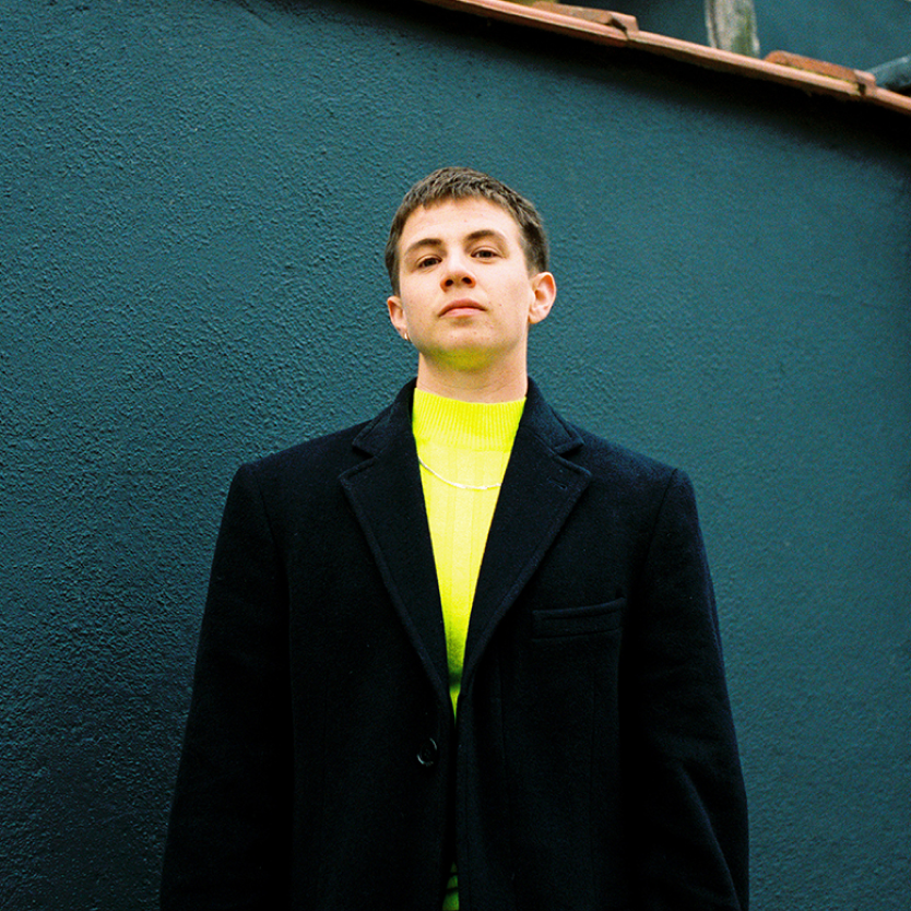 Transmasc person in neon yellow shirt and black blazer