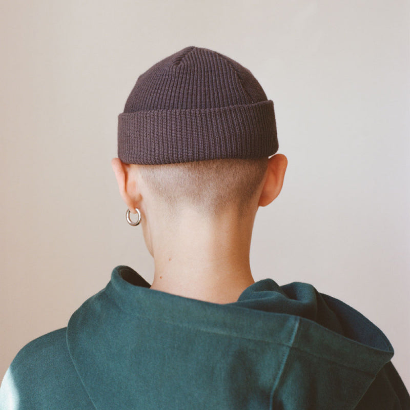 Portrait of a person in grey beanie and green hoody from behind