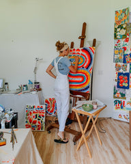 Artist at her easel painting large original fine art painting in art studio