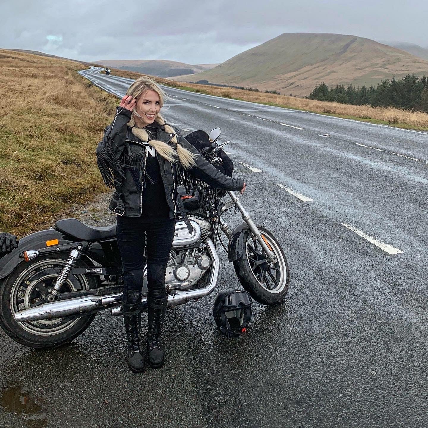 Lady Harley standing in the rain next to her motorcycle