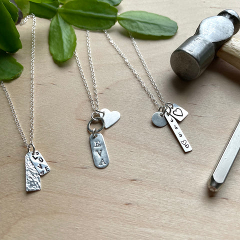Three silver necklace examples, geometric pendants decorated with stamped letters and hammered textures