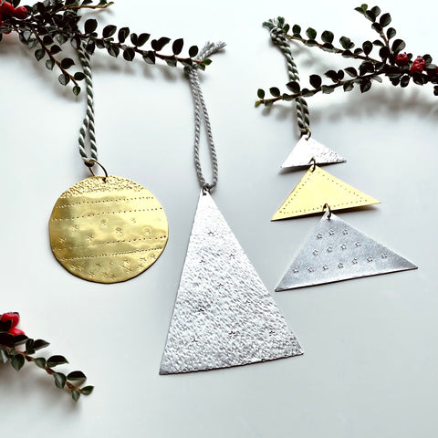 Festive metal hanging decorations flat bauble and tree shapes made from aluminium and brass, decorated with stamped symbols and patterns