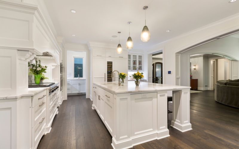 All-white kitchen with dark brown wood flooring