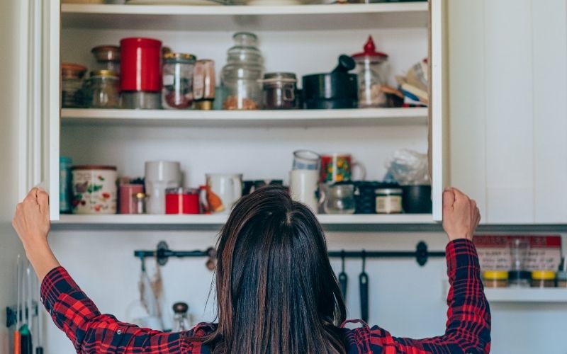 Woman figuring out how to organize the kitchen cabinet