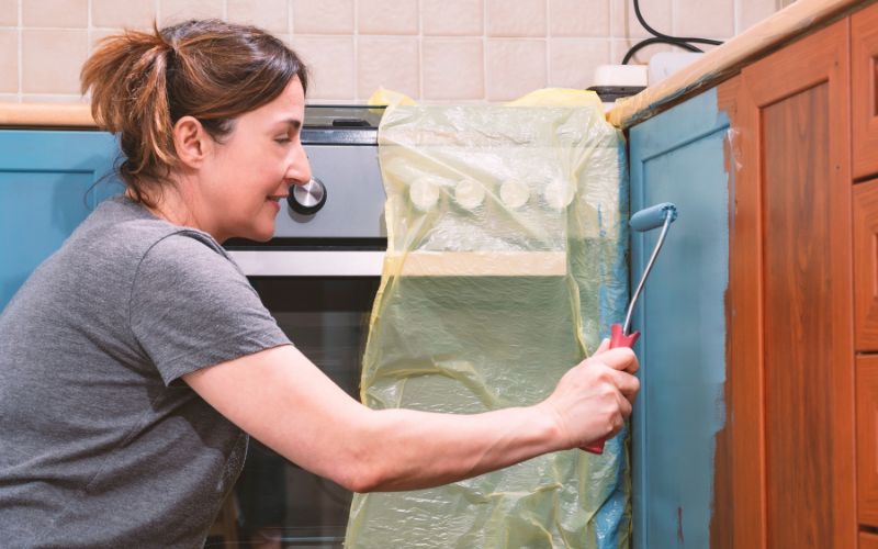 Woman painting a kitchen cabinet