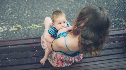 Mother breastfeeding baby in upright position or koala hold