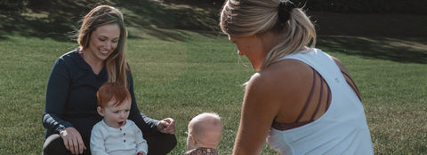 Two moms with their babies, sitting, smiling and facing each other