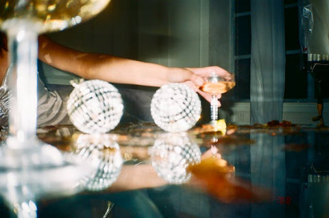A woman holding wine glass near lightning balls.