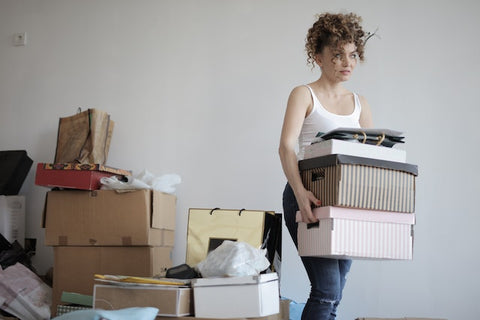 Woman carrying boxes next to a pile of clutter