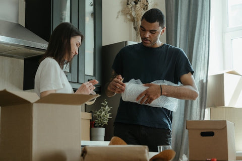 Man and woman using bubble wrap for packing