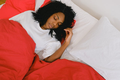 Woman sleeping in a bed with red blankets