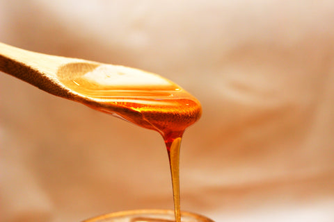 Honey dripping off a wooden spoon