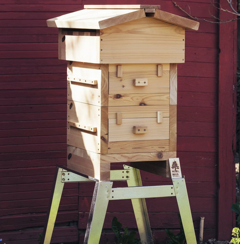 A Bee Built Universal Hive Stand next to a red shed
