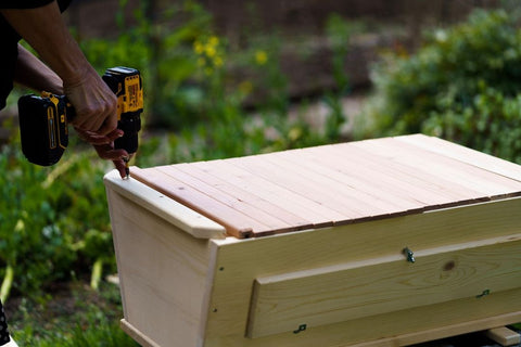Someone putting the finishing touches on a top bar hive with a power drill