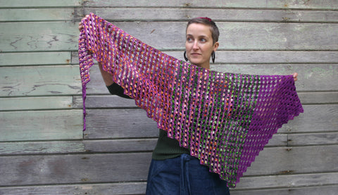 kira holds a wind and sea shawl, a triangular tunisian crocheted shawl that is our featured pattern of the month