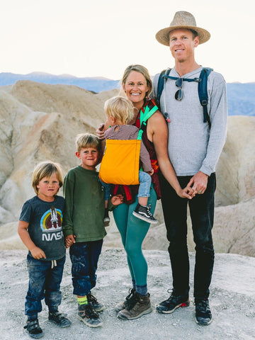 A family of 5 hiking in a scenic landscape with a child riding in a Trail Magik child carrier attached to a hiking backpack