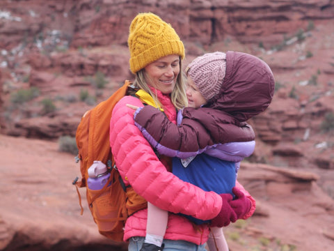 A woman hiking in the cold with her child in a Trail Magik kid carrier attached to her hiking pack