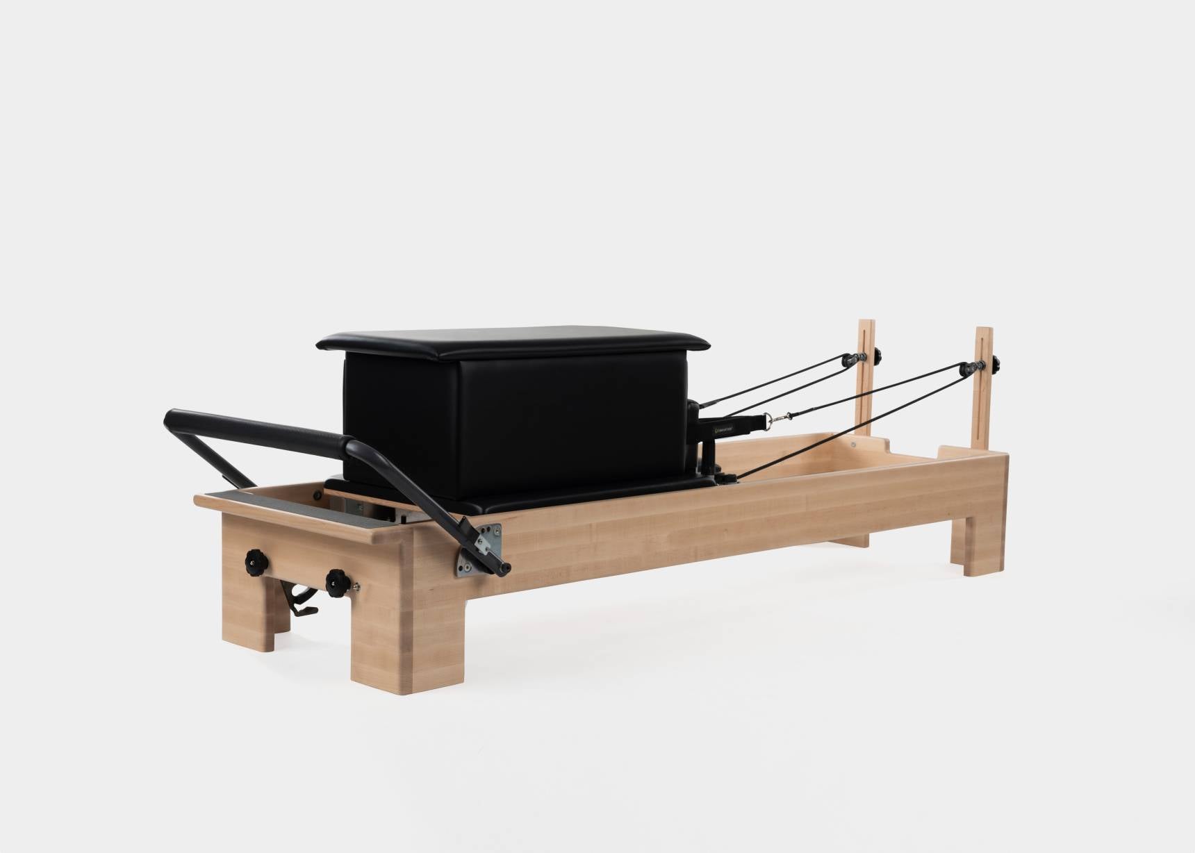 Black large sitting box positioned on a Pilates reformer.