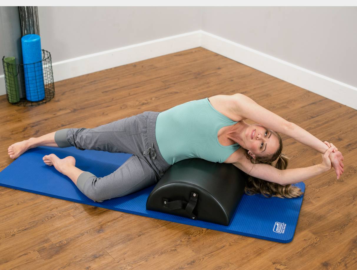 Woman stretching across East Coast Style Baby Arc on blue mat.