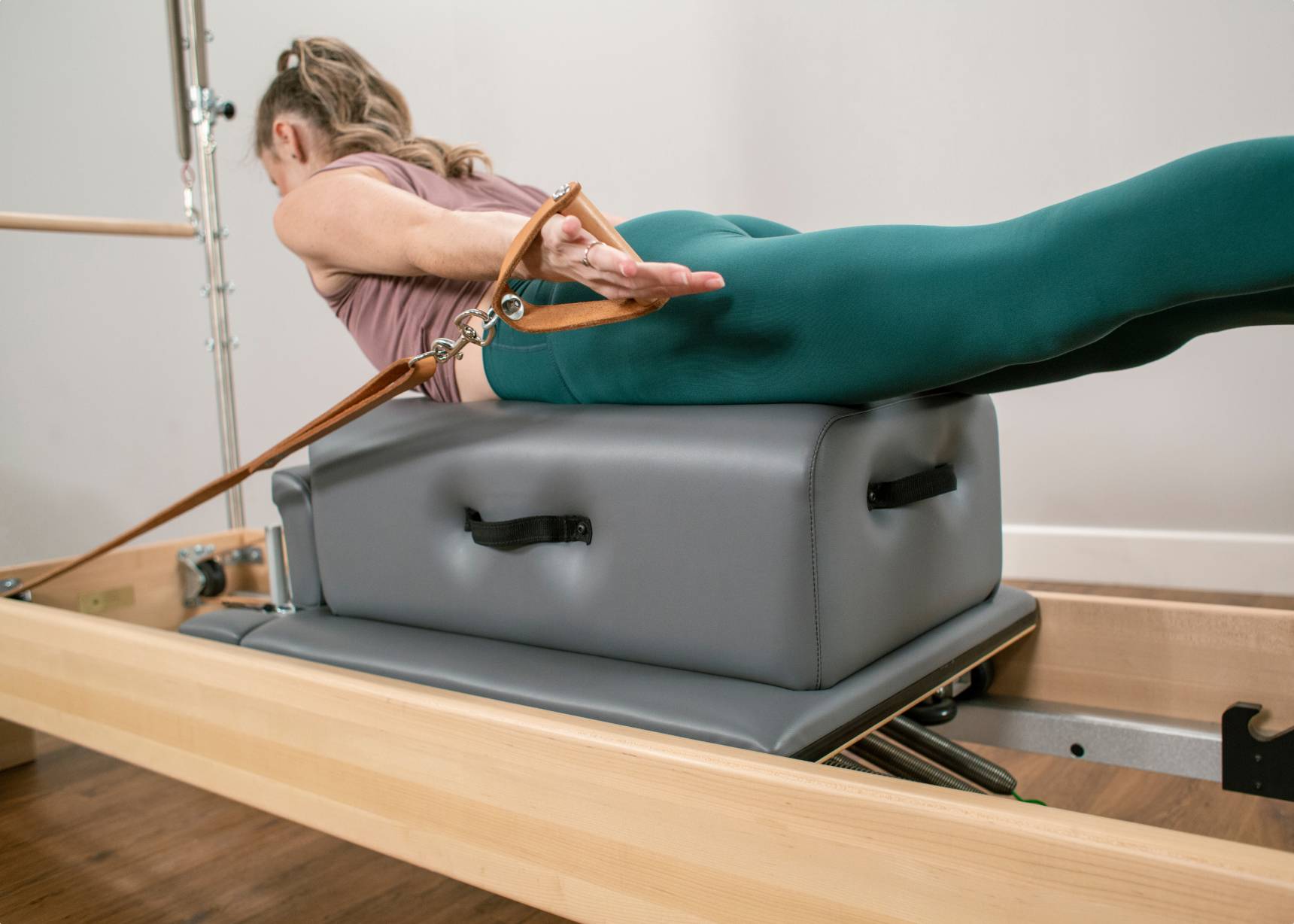 Woman exercising on a CenterLine Sitting Box on a reformer.