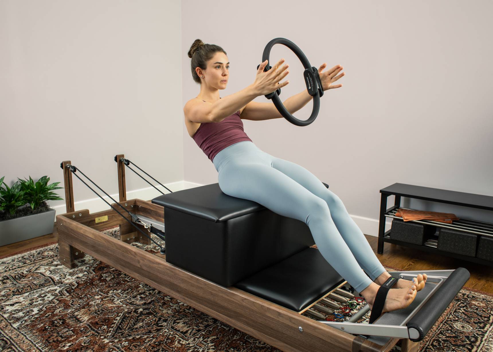 Woman using large sitting box on reformer with Ultra-Fit Circle.