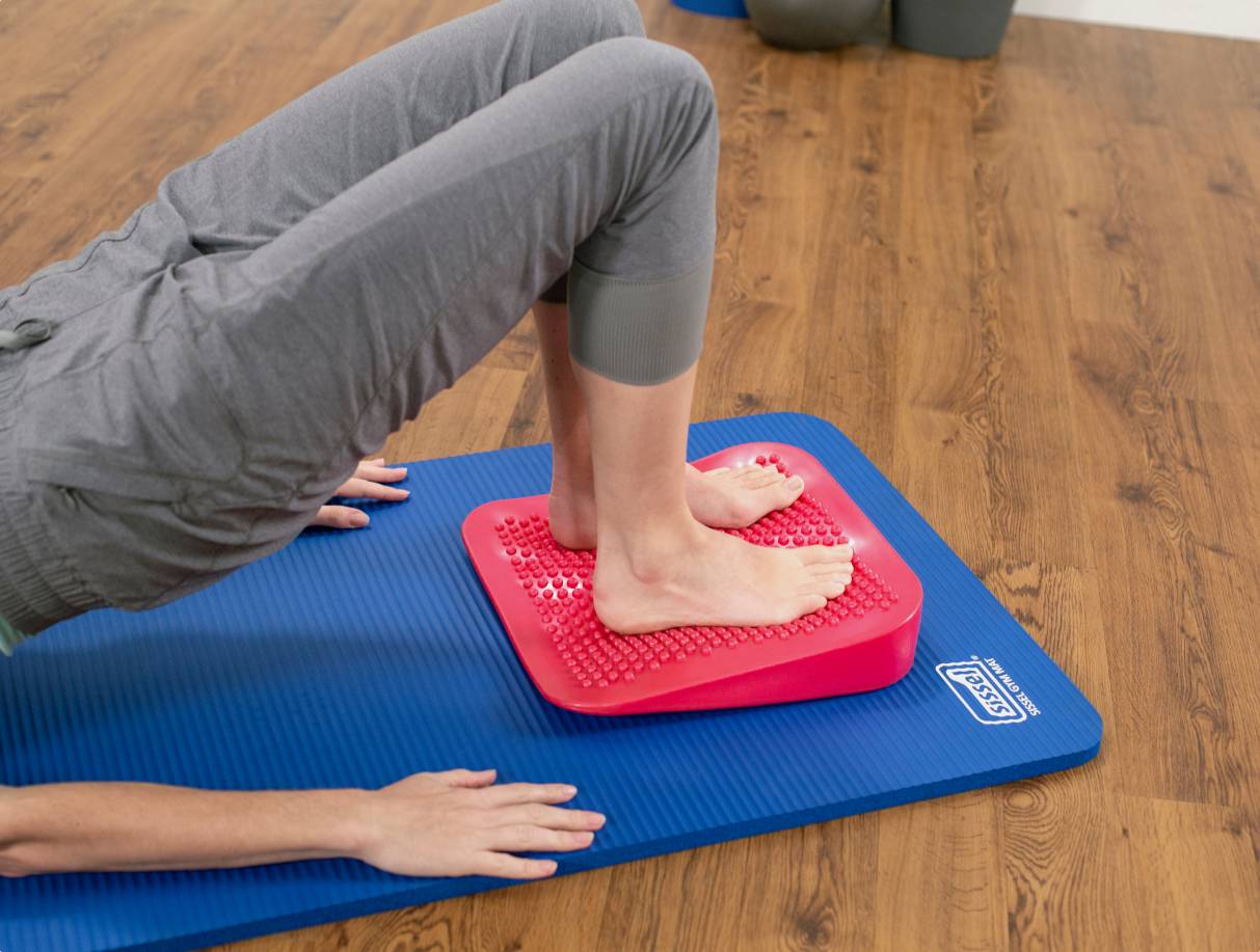 Inflatable Wedge being used by a student. This versatile prop helps to improve posture and alignment during exercises.