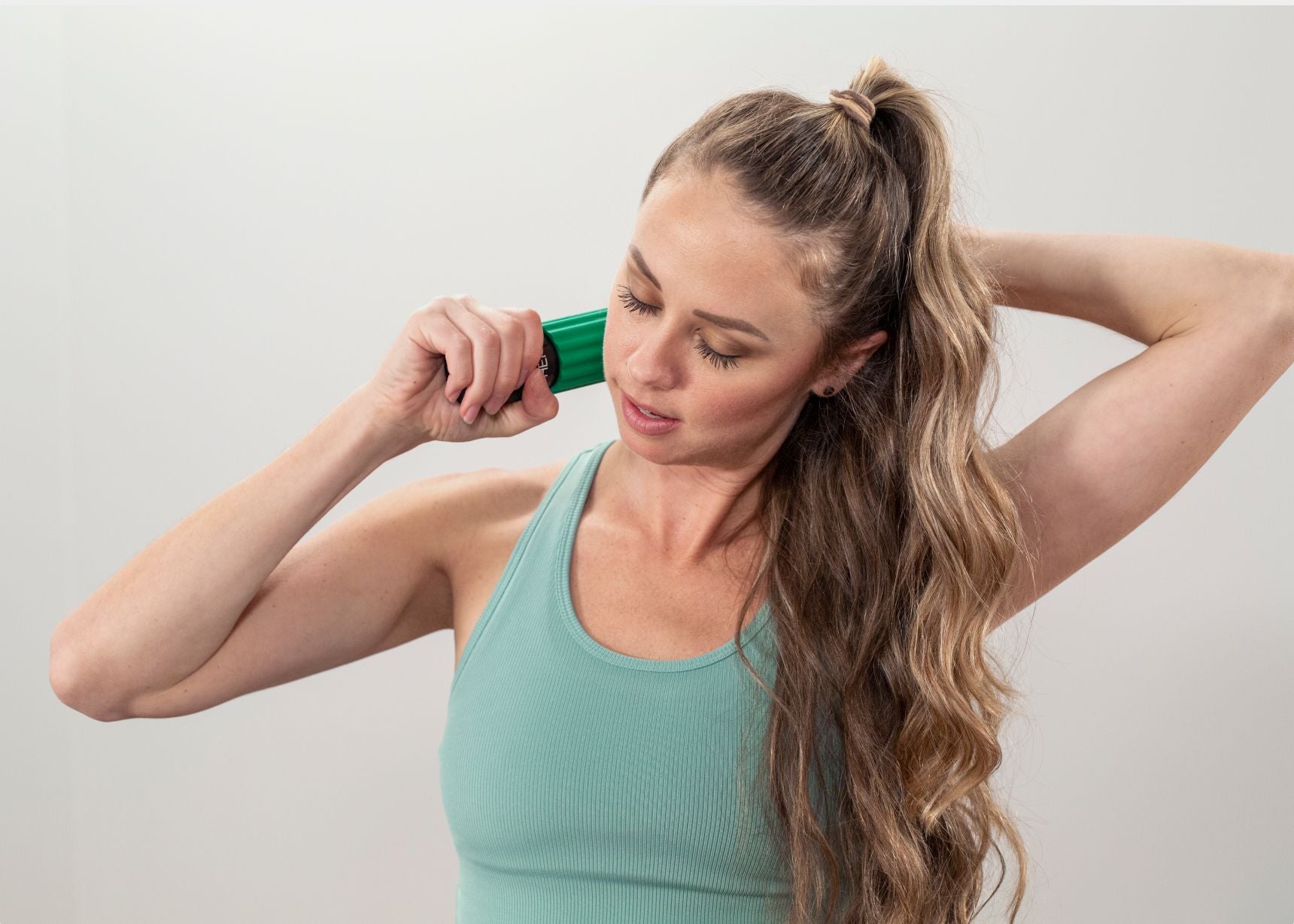 Woman using portable roller massager for neck tension relief.