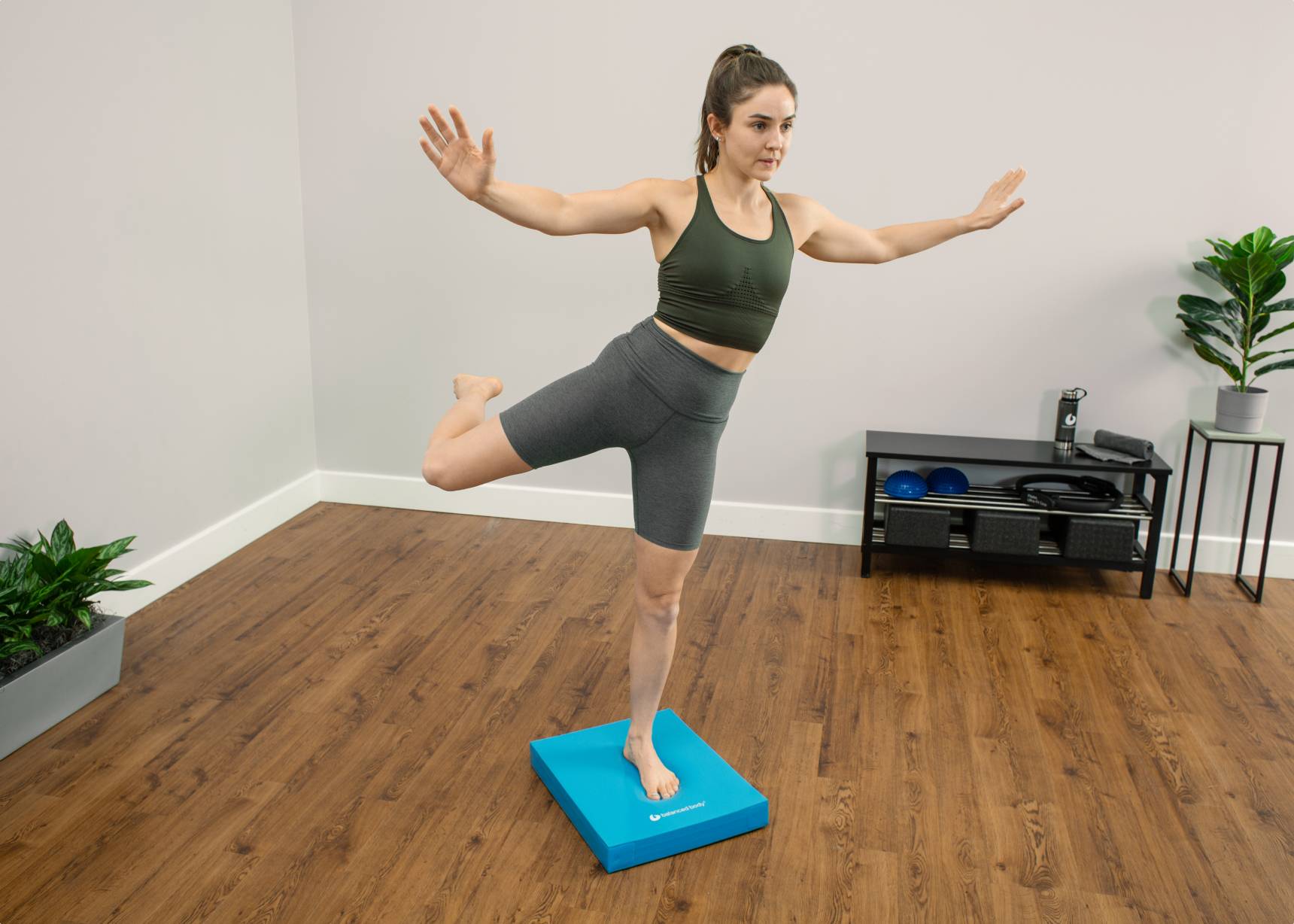 Woman balancing on one leg on a blue balance pad.