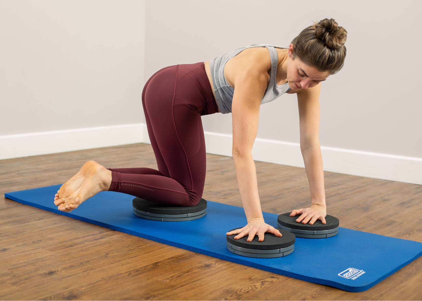 Woman doing All Fours Lateral Flexion on blue Sissel gym mat.