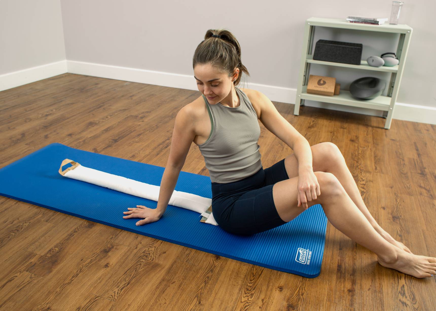 Woman using a white SmartSpine on blue Sissel gym mat.