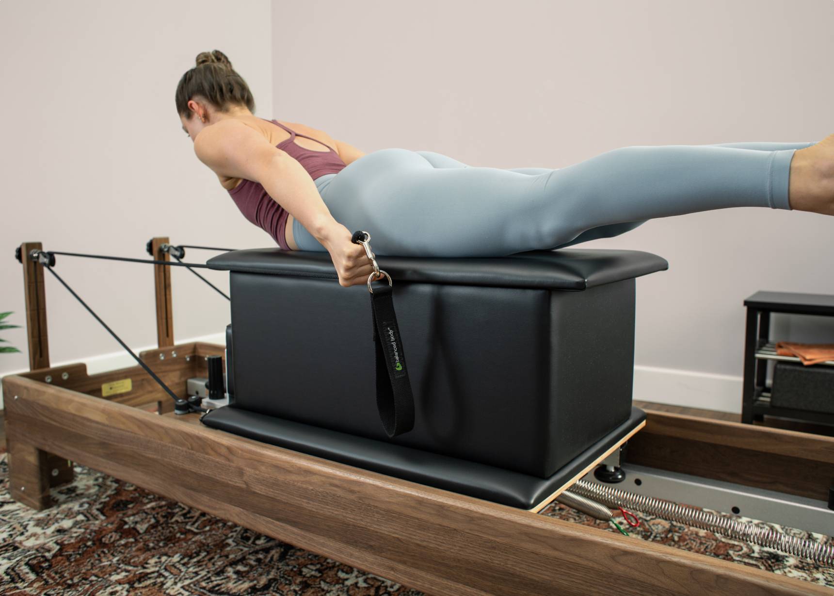 Woman using Large Sitting Box for Pilates exercises.