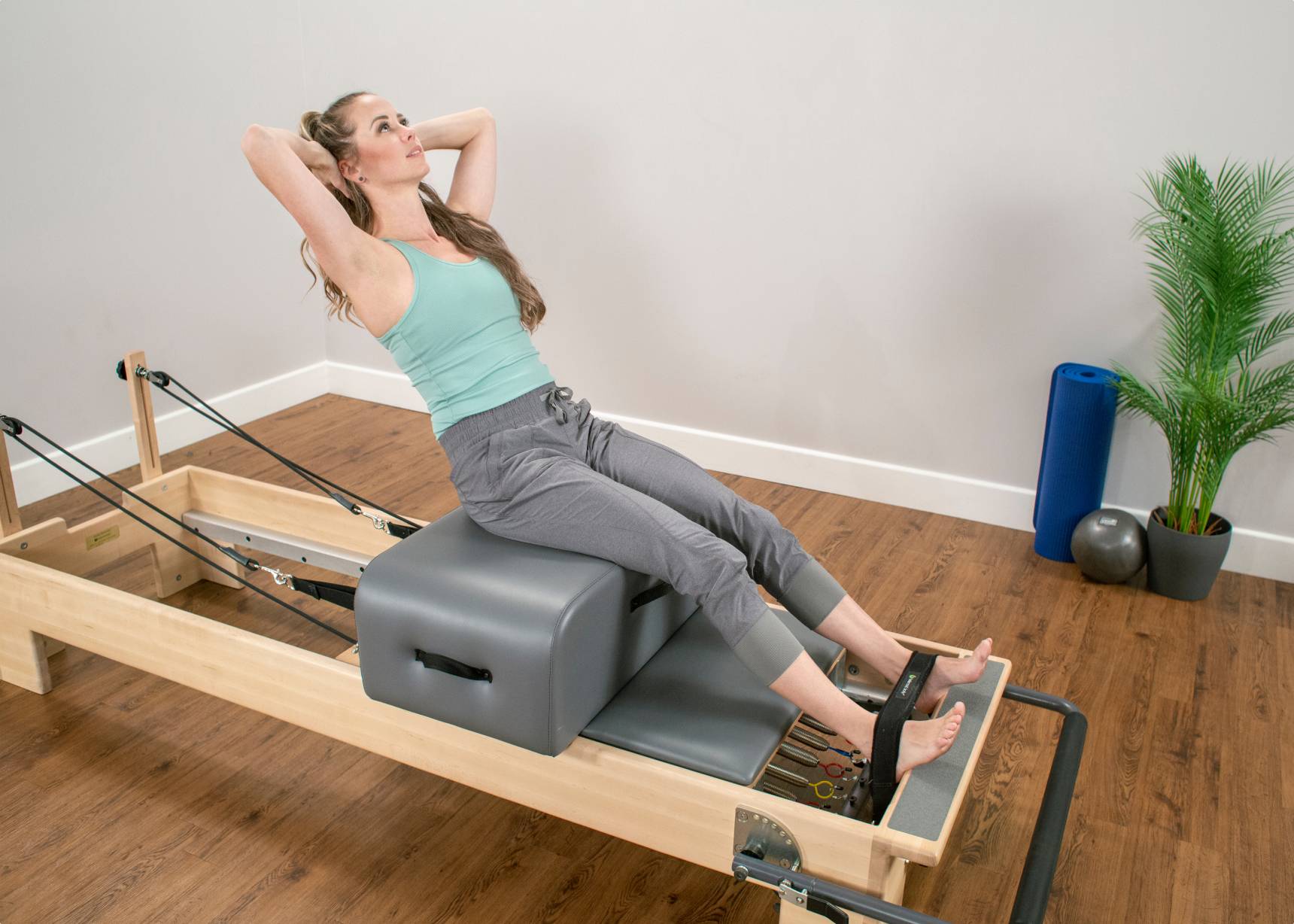Close-up of the Contour Sitting Box being used by a woman during a Pilates session.