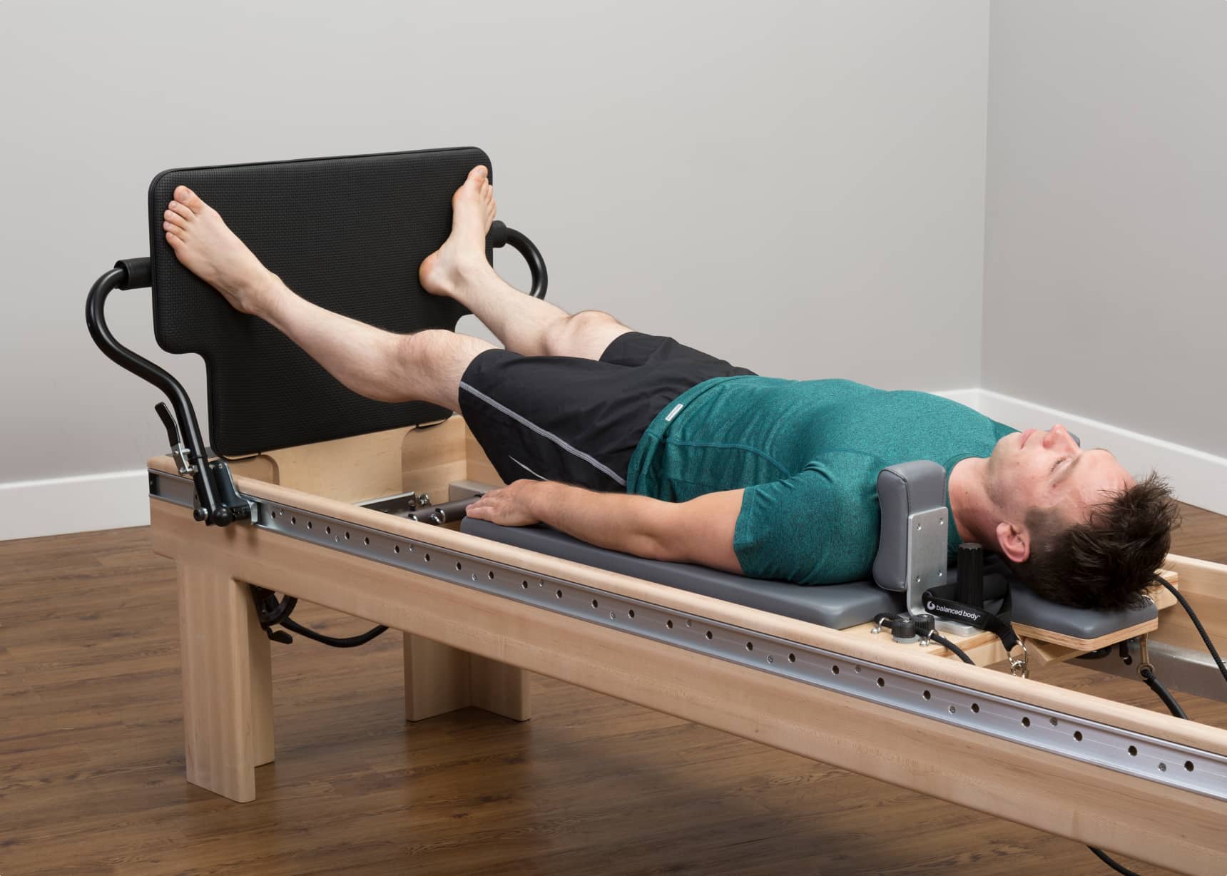 May laying on Pilates Reformer with feet against a jumpboard