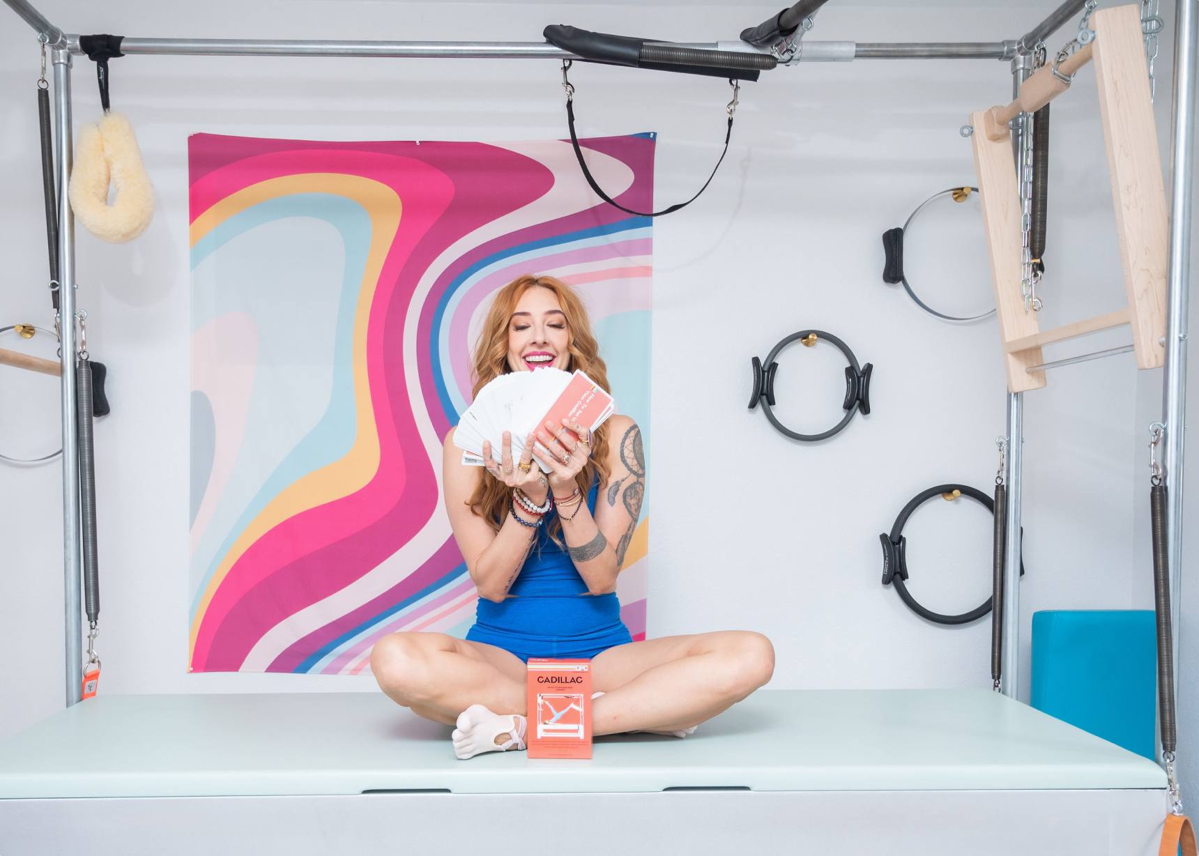 Woman holding a stack of Pilates exercise cards tailored for Cadillac Pilates.